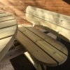 Timber smooth planed picnic table with seat backs and rounded edges on tarmac next to wooden building