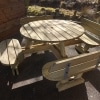 Traditional pub style picnic bench outside in sunshine near wooden building and nature