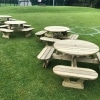 Multiple round picnic benches in tradition park style on a grass sports grounds near a football pitch